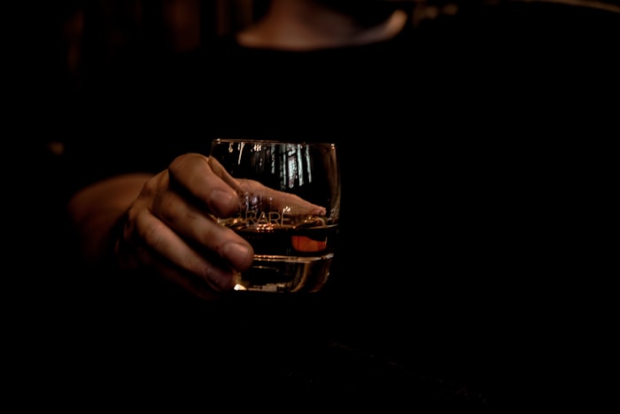 Glass of whisky held in hand — representing alcohol abuse