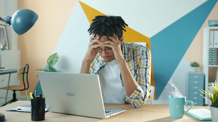 Frustrated man holding his head at a desk — representing anger management